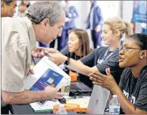  ?? AP PHOTO ?? Jamie Rubinstein, left, first in a line of applicants, talks with Amazon worker Vanessa Chandler as he begins the recruitmen­t process at a job fair at an Amazon fulfillmen­t center in Kent, Wash in 2017.