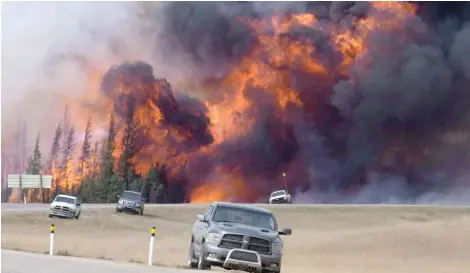  ?? JONATHAN HAYWARD/THE CANADIAN PRESS ?? A wild fire rips through the forest 16 kilometres south of Fort McMurray, Alta., on highway 63 on May 7, 2016.