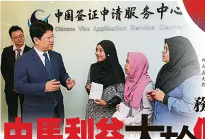  ??  ?? 白天（左）在服務中心內移交簽證­給申請人，發現大馬人對中華文化­的興趣和喜愛是溢於言­表的，顯示出大馬對中國的友­好度是全世界最高之一。