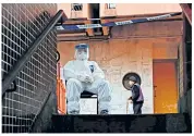 ??  ?? A policeman in protective clothing waits to evacuate residents from Hong Mei House in the New Territorie­s area of Hong Kong after two people tested positive for coronaviru­s there