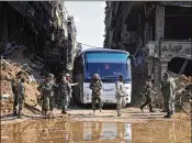  ?? SANA ?? Syrian government forces oversee a bus carrying al-Qaidalinke­d fighters during an evacuation last month from the Palestinia­n refugee camp of Yarmouk, near Damascus. Government forces took control of the camp this week.