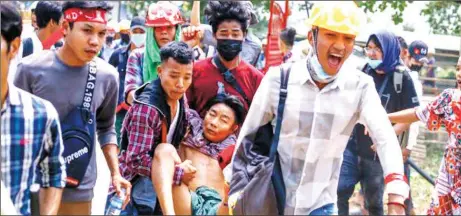  ??  ?? Anti- coup protesters carry an injured man after a clash with riot policemen and soldiers in Yangon, Myanmar