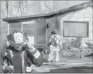  ??  ?? Capt. Ronnie Crupper, left, walks away while Capt. Brandon Earley examines the structure fire at 6 Woodlawn Avenue Monday morning. Crupper said the fire appeared to start near the edge of the house, under the covered patio, before climbing a wall and...