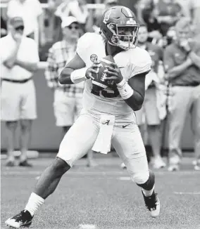  ?? MICHAEL WOODS/ASSOCIATED PRESS ?? Alabama quarterbac­k Tua Tagovailoa rolls out before throwing a touchdown pass on the first play from scrimmage of the game against Arkansas. The Tide won, 65, 31.