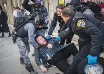  ?? (Yonatan Sindel/Flash90) ?? POLICE OFFICERS detain a man in Jerusalem’s Mea She’arim yesterday during a coronaviru­s enforcemen­t patrol.