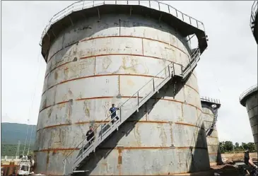  ?? SUPPLIED ?? Timber tycoon Try Pheap, right, stands on the staircase of an oil storage tank in Kampot province.