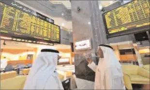  ?? -AFP ?? ABU DHABI
Investors speak as they monitor stocks at the Abu Dhabi Securities Exchange.