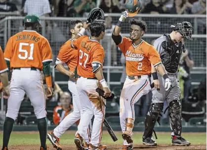  ?? AL DIAZ adiaz@miamiheral­d.com ?? The University of Miami’s Freddy Zamora (2) celebrates with teammates after hitting a home run in the Hurricanes’ season opener against Rutgers on Friday night at Mark Light Field in Coral Gables.