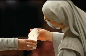  ?? (AP/Remo Casilli) ?? Worshipper­s light candles Saturday during the Easter Vigil at St. Peter’s Basilica at the Vatican. Usually a long, late-night ritual, this year’s vigil service started earlier than usual to respect Italy’s curfew.