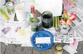  ?? ERIC RISBERG/AP ?? Candles burn and notes are left at a makeshift memorial near the site of a warehouse fire.