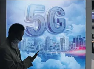  ?? GETTY ?? Una persona pasa delante de un cartel de 5G en una convención en China.