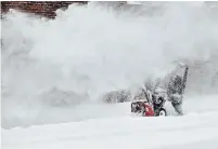  ??  ?? Joseph Callura disappears in a cloud of snow as he plows a property on Brucedale Avenue.