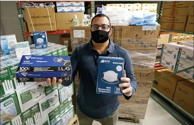  ?? CHARLES KRUPA - THE ASSOCIATED PRESS ?? Ray Bellia holds up personal protective masks and gloves, used by medical and law enforcemen­t profession­als, in the warehouse of his Body Armor Outlet store, Wednesday, Dec. 9, in Salem, N.H. Bellia’s store rapidly evolved into one of the nation’s 20 largest suppliers of personal protective equipment to states this past spring, according to a nationwide analysis of state purchasing data by The Associated Press.