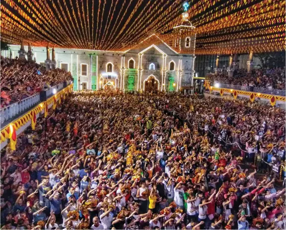  ?? ALDO NELBERT BANAYNAL ?? Devotees wave their hands and their images of Señor Santo Niño while singing the Gozos at the Basilica Pilgrim Center after the procession from Fuente Osmeña.