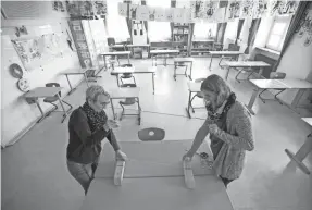  ?? ALEX GRIMM/GETTY IMAGES ?? Staff install a plexiglass pane on the teacher’s table April 21 during preparatio­ns for reopening a school in Heppenheim, Germany.