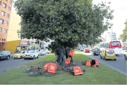  ?? AP PHOTOS ?? Venezuelan couriers wait under a tree for messages from the Rappi applicatio­n to make deliveries in Bogota, Colombia, Wednesday, July 17, 2019.