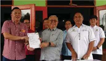  ?? ?? Sikie (centre) hands over the documents to a representa­tive of the contractor.