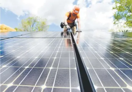  ??  ?? Custom Solar’s Houston Sherer works to install solar panels on a home in Boulder earlier this month.