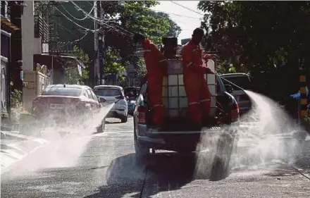  ?? EPA PIC ?? City Hall workers disinfecti­ng streets near an area under lockdown in Quezon City, Metro Manila, yesterday.