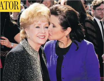  ?? CHRIS PIZZELLO / THE ASSOCIATED PRESS FILES ?? Hollywood icon Debbie Reynolds died at the age of 84 on Wednesday, one day after the death of her daughter Carrie Fisher, shown planting a kiss on her mother’s cheek at the Emmy Awards in 2011.
