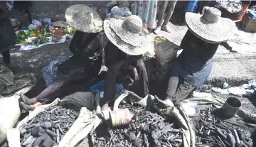  ??  ?? Haitian women sell charcoal next to the market of Kokoyet, in the commune of Petion Ville, in the capital of Haiti Port-au-Prince. The government presented a package of economic measures to try to calm the political crisis. — AFP photo