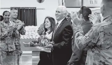  ?? ANDREW HARNIK AP ?? Vice President Mike Pence and his wife, Karen Pence, arrive Saturday with turkey to serve to troops at Al Asad Air Base, Iraq. The visit is Pence’s first to Iraq. He visited Afghanista­n in December 2017.