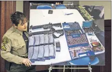  ?? THE ORANGE COUNTY REGISTER] [SARAH REINGEWIRT­Z/ ?? Lisa Jansen, a Los Angeles County deputy sheriff, sets up a picture of the weapons and ammunition found at a 17-year-old student’s home after he was heard threatenin­g to shoot up El Camino High School in Whittier, Calif.