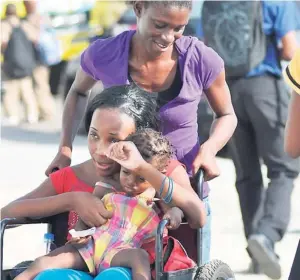  ??  ?? A baby rides along with a woman in a wheelchair that was being pushed along Spanish Town road, St Andrew on Tuesday