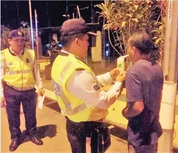  ??  ?? A motorist undergoes a breathalys­er test during the operation at Jalan Kubu.