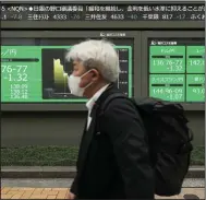  ?? (AP/Hiro Komae) ?? A man walks by monitors showing the Japanese yen against other foreign currencies at a securities firm in Tokyo on Thursday.