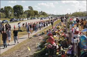  ?? DAVID SANTIAGO/MIAMI HERALD FILE PHOTOGRAPH ?? Parents and students walk next to the memorial for the victims of the shooting at Marjory Stoneman Douglas High School on Feb. 25, 2018, for an open house as parents and students returned to the school for the first time since 17 victims were killed in a mass shooting at the school in Parkland, Fla., on Feb. 14, 2018.