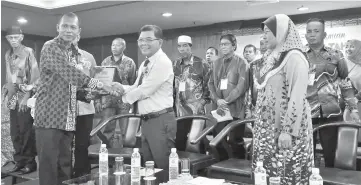  ??  ?? Arifin (middle) receives a memento from Rubail. Also seen is Lipah.