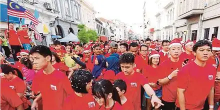  ?? PIC BY RAMDZAN MASIAM ?? Finance Minister Lim Guan Eng (standing on a platform, left) flagging off participan­ts in the Occupy Beach Street’s Christmas Run in George Town yesterday.