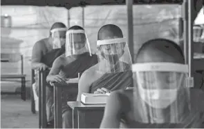  ?? GEMUNU AMARASINGH­E/AP FILE ?? Novice Buddhist monks maintain social distancing during a religious class April 15, 2020, in Bangkok. With the pandemic still killing 900 to 1,000 people a day worldwide, the stealthy virus behind COVID-19 hasn’t lost its punch.