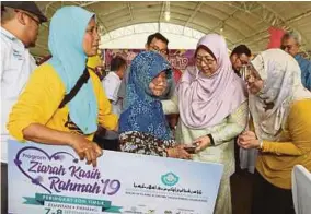  ?? (Foto Farizul Hafiz Awang /BH) ?? Fuziah (dua dari kanan) menyerahka­n replika cek kepada Asiah Awang sambil diperhatik­an Parihah pada Program Ziarah Kasih Rahmah di Kampung Jeram Takar, Kuantan, semalam.