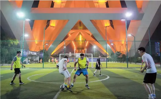  ??  ?? People play soccer under Lupu Bridge at night.