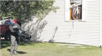  ?? JEFF KOWALSKY/ AFP VIA GETTY IMAGES ?? A person cleans up debris from a broken window at a home FBI agents searched in Hartland Township late Wednesday night and Thursday morning in connection with the kidnapping plot.