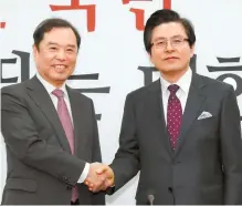 ?? Yonhap ?? Former Prime Minister Hwang Kyo-ahn, right, shakes hands with the main opposition Liberty Korea Party’s interim leader Kim Byung-joon at the National Assembly, Tuesday, after joining the conservati­ve party.