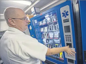  ?? [ADAM CAIRNS/DISPATCH] ?? Jackson Township Fire Department Capt. Bill Dolby demonstrat­es the use of a fingerprin­t ID security measure on a vending machine that distribute­s medication­s and first-aid supplies. Dolby said the machines have cut the cost of expired medication­s from...