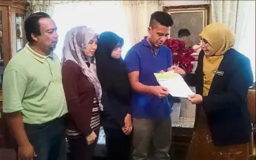  ??  ?? Helping hand: Noorhanita (right) handing over a cheque for RM1,500 in aid to Hamidah’s son Sharizal as his uncle Mat Razali Abdul Rahman and sisters Noor Shairah (second from left) and Noor Sherina look on in Kampung Rapat Jaya Tambahan, Ipoh.