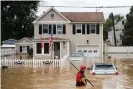  ?? Tom Brenner/AFP/Getty Images ?? A rescue crew member wades through high waters following a flash flood, as Tropical Storm Henri makes landfall, in Helmetta, New Jersey, on Sunday. Photograph: