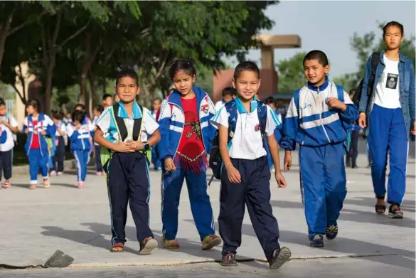  ?? 摄影 陈建/人民画报 ?? 清晨，阿拉尔市的小学生们结­伴走在上学的路上。