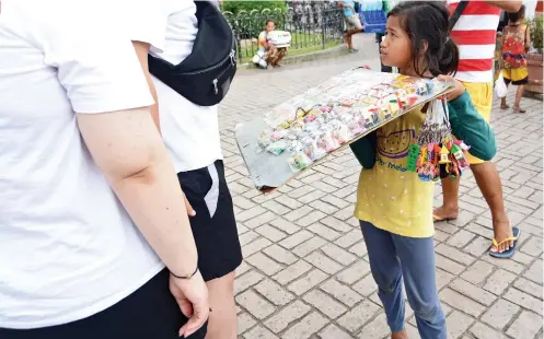  ?? SUNSTAR FOTO / ALEX BADAYOS ?? HELPING HER FAMILY. When she doesn’t have classes, 11-yearold Loreen Baar helps her family by selling souvenirs to tourists in Plaza Sugbo, near the Cebu City Hall and Basilica Minore del Sto. Niño.