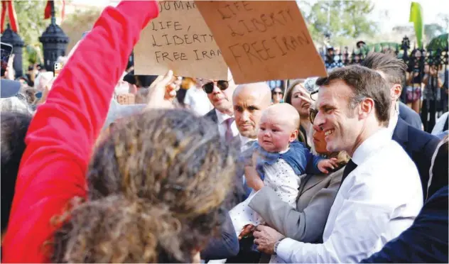  ?? Agence France-presse ?? ↑
A woman holds signs in support of Iranian women as French President Emmanuel Macron greets people in New Orleans, Louisiana, on Friday.