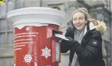  ?? PICTURE: JON SAVAGE ?? 0 Chloe Melhuish tries out the new ‘singing postbox’s on the High Street in Edinburgh’s Old Town yesterday. The Royal Mail’s postboxes play the sound of sleigh bells.