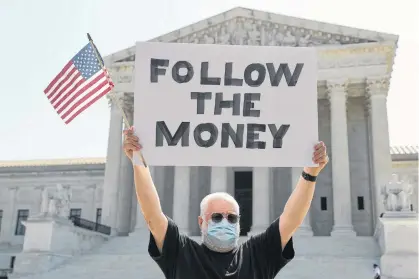  ?? REUTERS ?? Bill Christeson holds a sign reading “follow the money” in anticipati­on of justices ruling on U.S. President Donald Trump’s bid to block his financial records from being obtained by third parties, outside the U.S. Supreme Court in Washington.