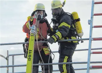  ?? FOTO: MARTIN BAUCH ?? Mit Atemschutz­gerät arbeiten die Feuerwehrl­eute auf einem Gerüst.