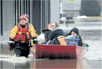  ?? BEN MIKESELL/ THE ASSOCIATED PRESS ?? Goshen, Ind., firefighte­rs pull a boat containing three women who were rescued after heavy flooding.