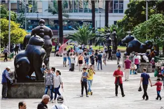  ?? Photos by Fernando Vergara/Associated Press ?? Visitors stroll Botero Plaza on Feb. 1 in Medellin, Colombia. The city was once the heart of a brutal war with drug cartels, but a sharp dip in violence attracted a flood of tourists.