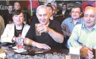  ?? (Courtesy) ?? PRIME MINISTER Benjamin Netanyahu holds a toast with Russian immigrants and former MK and Likud Knesset candidate Tali Ploskov (left) at a pub in Rishon Lezion.